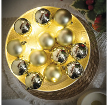 Globuri decorative de Crăciun aurii pe o farfurie cu un lanț luminos