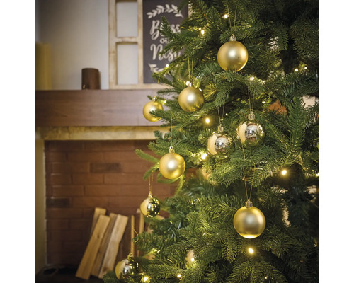 Brad împodobit cu globuri aurii și argintii și lumini într-o sufragerie cu șemineu