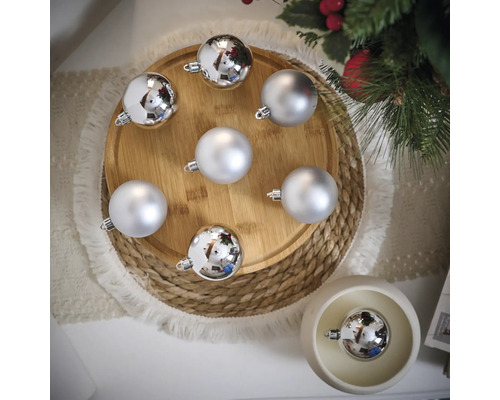 Globuri decorative argintii de Crăciun pe o farfurie de lemn