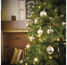 Pom de Crăciun împodobit cu globuri argintii și luminițe într-o atmosferă de living