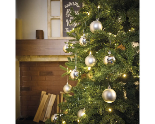 Pom de Crăciun împodobit cu globuri argintii și luminițe într-o atmosferă de living