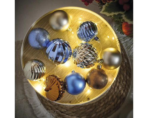 Globuri de Crăciun multicolore pe o tavă din lemn iluminată