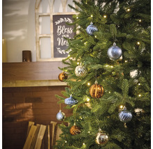 Brad împodobit cu diverse globuri de Crăciun și un șir de lumini în sufragerie.