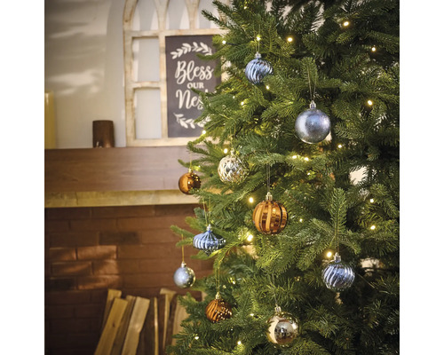 Brad împodobit cu diverse globuri de Crăciun și un șir de lumini în sufragerie.