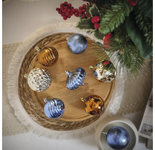 Globuri multicolore de Crăciun pe o tavă de lemn lângă un pom de Crăciun.