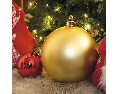 Glob mare de Crăciun de culoare aurie în fața unui pom de Crăciun