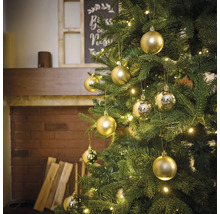 Brad împodobit cu globuri aurii și lumini într-o cameră cu șemineu.