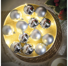 Globuri argintii de Crăciun pe o tavă de lemn iluminată