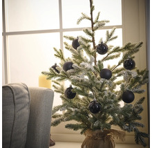 Brad decorativ de Crăciun, acoperit cu zăpadă, cu globuri negre într-un sac de iută