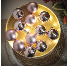 Globuri decorative de Crăciun în roz pe o tavă de lemn cu lumini