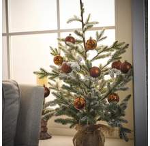 Brad împodobit, acoperit cu zăpadă, cu globuri maro într-un sac de iută