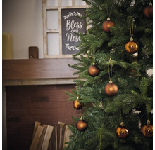 Brad împodobit cu globuri în fața șemineului