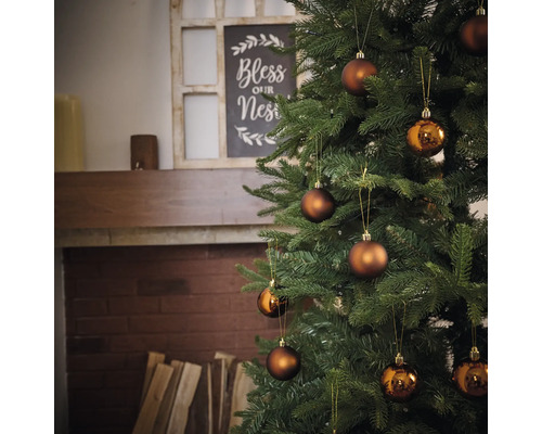 Brad împodobit cu globuri în fața șemineului