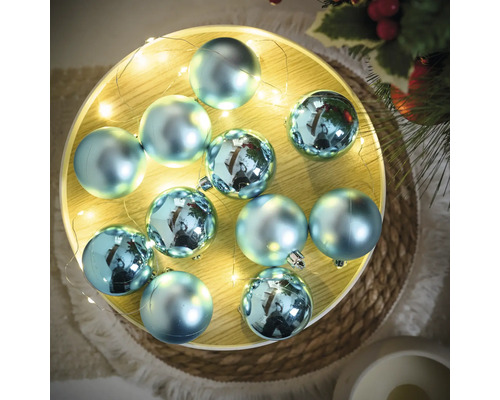 Globuri decorative albastre de pom de Crăciun pe o tavă cu șir de lumini