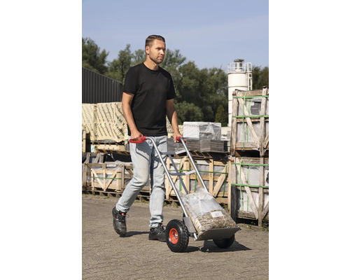 Bărbat transportă mărfuri în sac cu un cărucior în aer liber