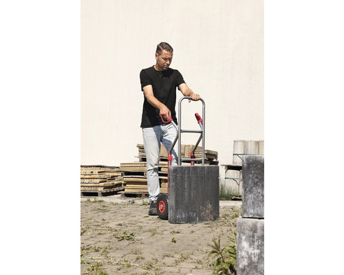 Un bărbat transportă pietre de pavaj cu un cărucior.