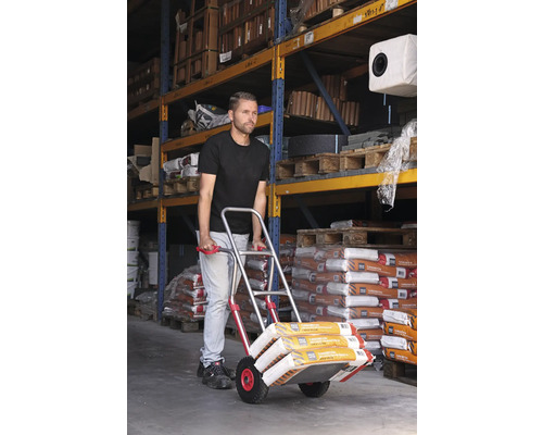 Un bărbat transportă saci cu un cărucior într-un depozit.