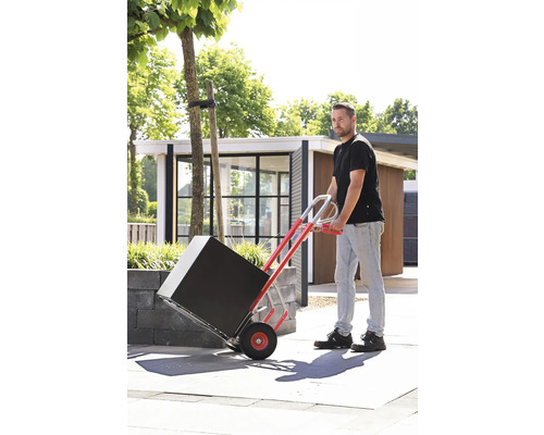 Un bărbat transportă un pachet negru cu un cărucior în aer liber.