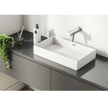 Baie modernă cu lavoar, baterie, bețișoare parfumate și dozatoare de loțiune pe un dulap de lavoar gri.