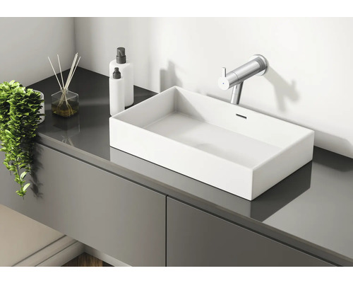 Baie modernă cu lavoar, baterie, bețișoare parfumate și dozatoare de loțiune pe un dulap de lavoar gri.