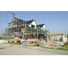 Construcție nouă a unei case cu schelă, betonieră și materiale de construcție.