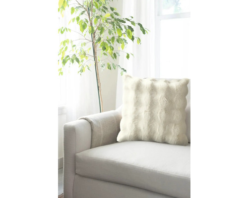 Pernă decorativă pe o canapea lângă o plantă de interior.