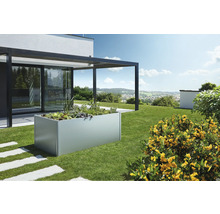 Jardinieră înaltă din metal în grădină cu plante și terasă adiacentă