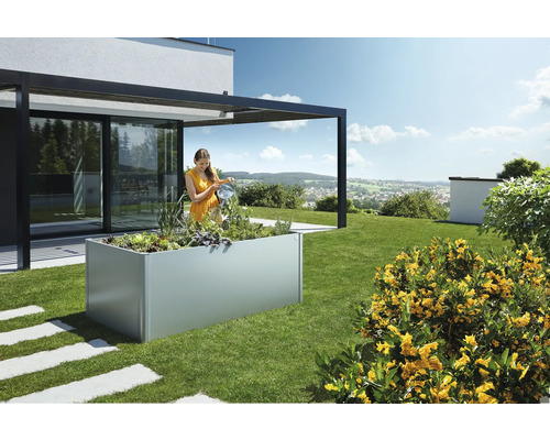 Femeie udând plante într-o jardinieră supraînălțată în grădină