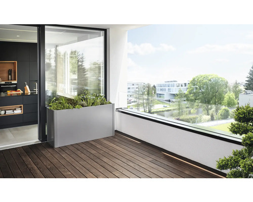 Scenă de balcon cu o jardinieră metalică, plantată cu ierburi și plante, pe o podea de lemn