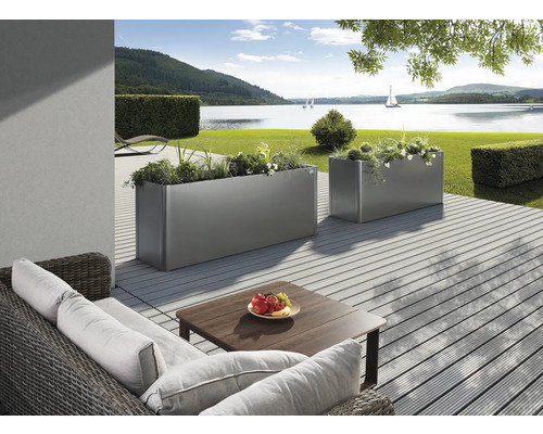 Două jardiniere metalice dreptunghiulare plantate pe o terasă cu vedere la lac.