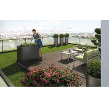 Grădină pe acoperiș cu femeie, jardiniere, mobilier și plante pe fundal urban