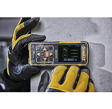 Sigla DeWALT pe un telemetru laser digital ținut de mănuși de lucru