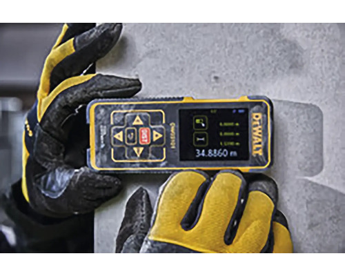 Sigla DeWALT pe un telemetru laser digital ținut de mănuși de lucru