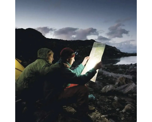 Doi oameni cu lanterne frontale se uită la o hartă afară noaptea.