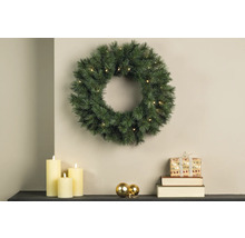 Scenă de Crăciun cu coroniță de brad iluminată, lumânări și cadou