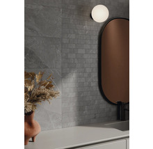 Baie cu plăci de perete gri cu aspect de piatră, oglindă și lampă