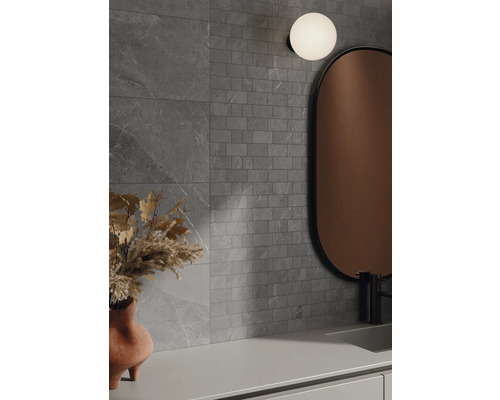 Baie cu plăci de perete gri cu aspect de piatră, oglindă și lampă