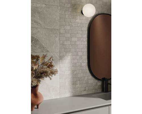 Decor de perete cu plăci cu aspect de piatră și plăci de mozaic, combinate cu o oglindă și o lampă