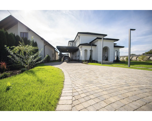 Alee cu pavaj în fața unei case moderne cu carport și grădină îngrijită