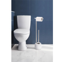 Toaletă de podea cu suport pentru hârtie igienică și set de perii WC în baie.