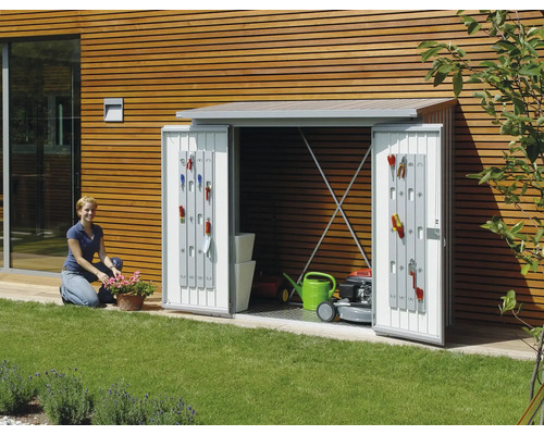 Dulap de grădină cu uși deschise, echipat cu unelte de grădinărit, mașină de tuns iarba și stropitoare în grădină.