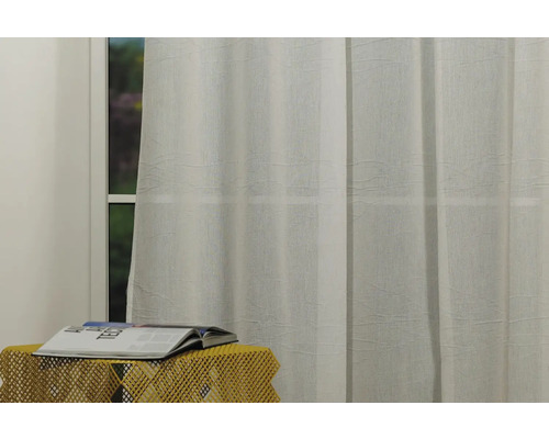 Fereastră cu perdea deschisă la culoare și revistă pe masă mică