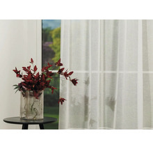Fereastră decorativă cu perdea transparentă și vază cu flori pe o masă