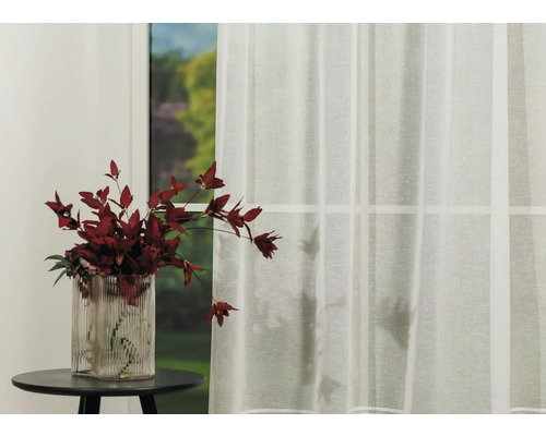 Fereastră decorativă cu perdea transparentă și vază cu flori pe o masă