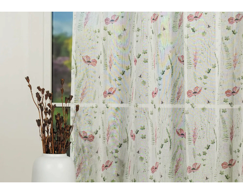 Șaluri decorative cu model floral în fața unei ferestre.