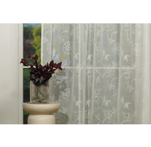 Cortină decorativă cu model floral în fața unei ferestre.