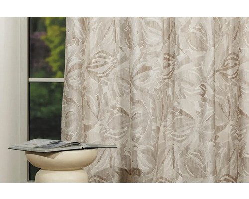 Cortină decorativă cu model floral și o bancă cu o carte pe ea în fața unei ferestre.