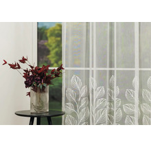 Fereastră decorativă cu perdea transparentă cu frunze și vază cu flori pe o masă