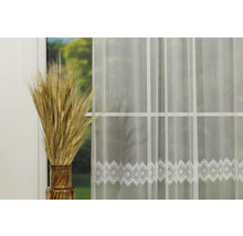 Material decorativ, transparent pentru perdele, cu bordură filigranată în fața unei ferestre cu spice de grâu într-o vază