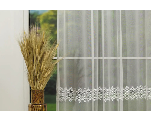 Material decorativ, transparent pentru perdele, cu bordură filigranată în fața unei ferestre cu spice de grâu într-o vază